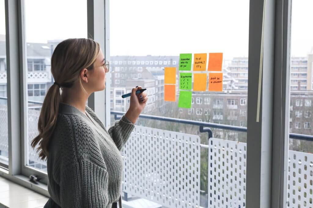 A lady in front of sticky notes on a glass window : Mid-Level Career Shift: Navigating a Job change in the Creative Industry