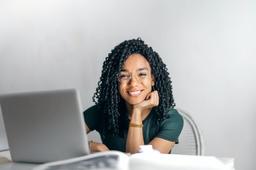 A smiling lady seated in front of a laptop - Content writer Needed