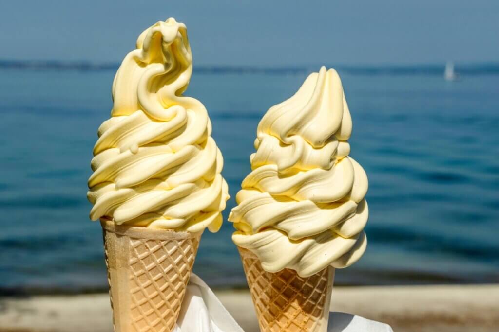A Picture of two ice cream cones with a sea as the background