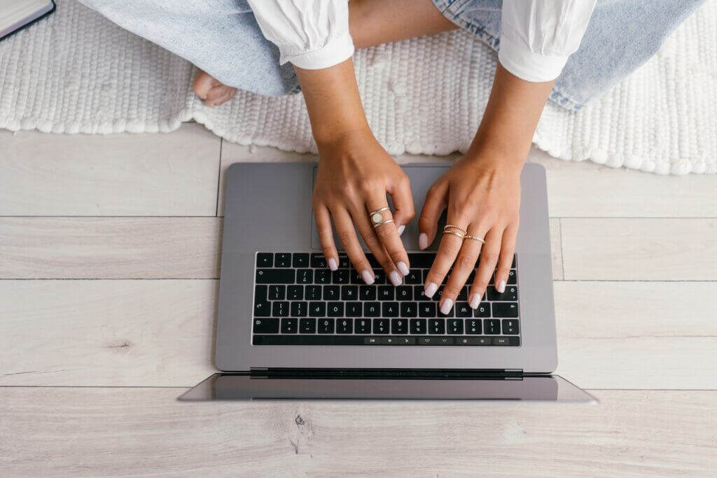 A lady sitting crosslegged with her hands on a laptop