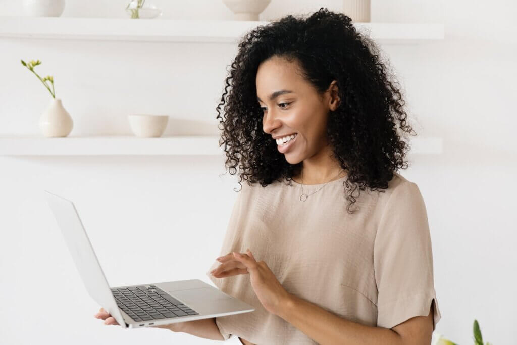 A black woman holding a laptop and smiling