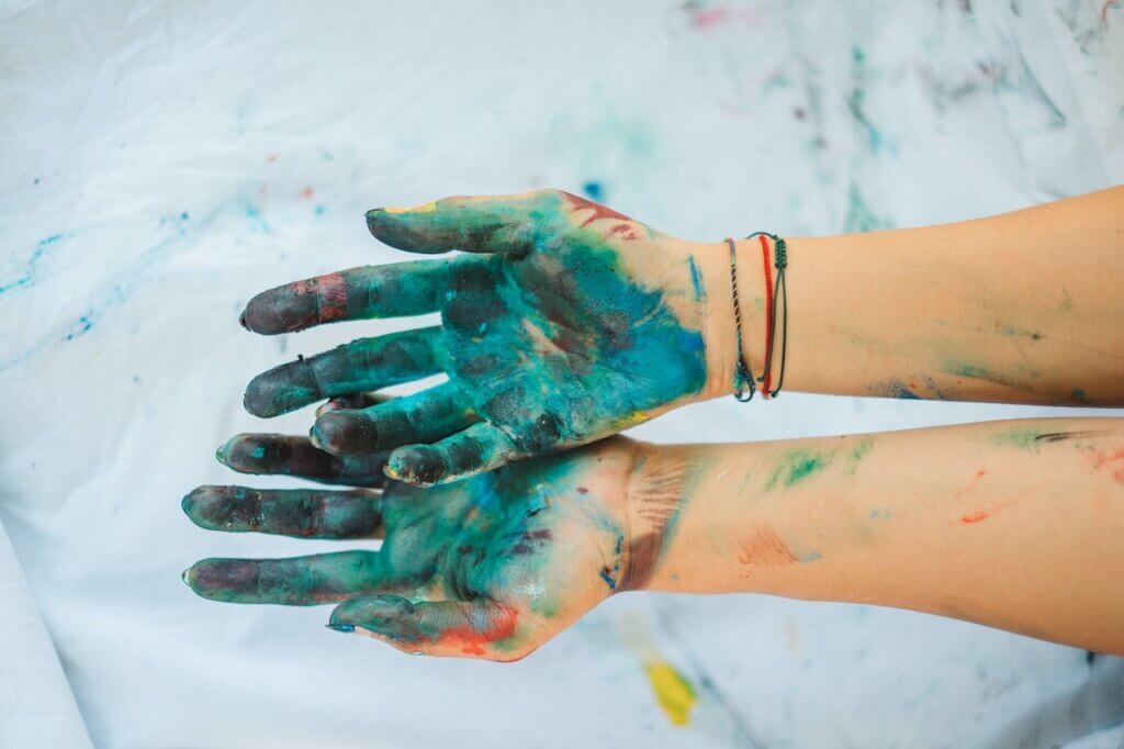 Two hands covered in paint to advocate for environmentally sustainable art practise